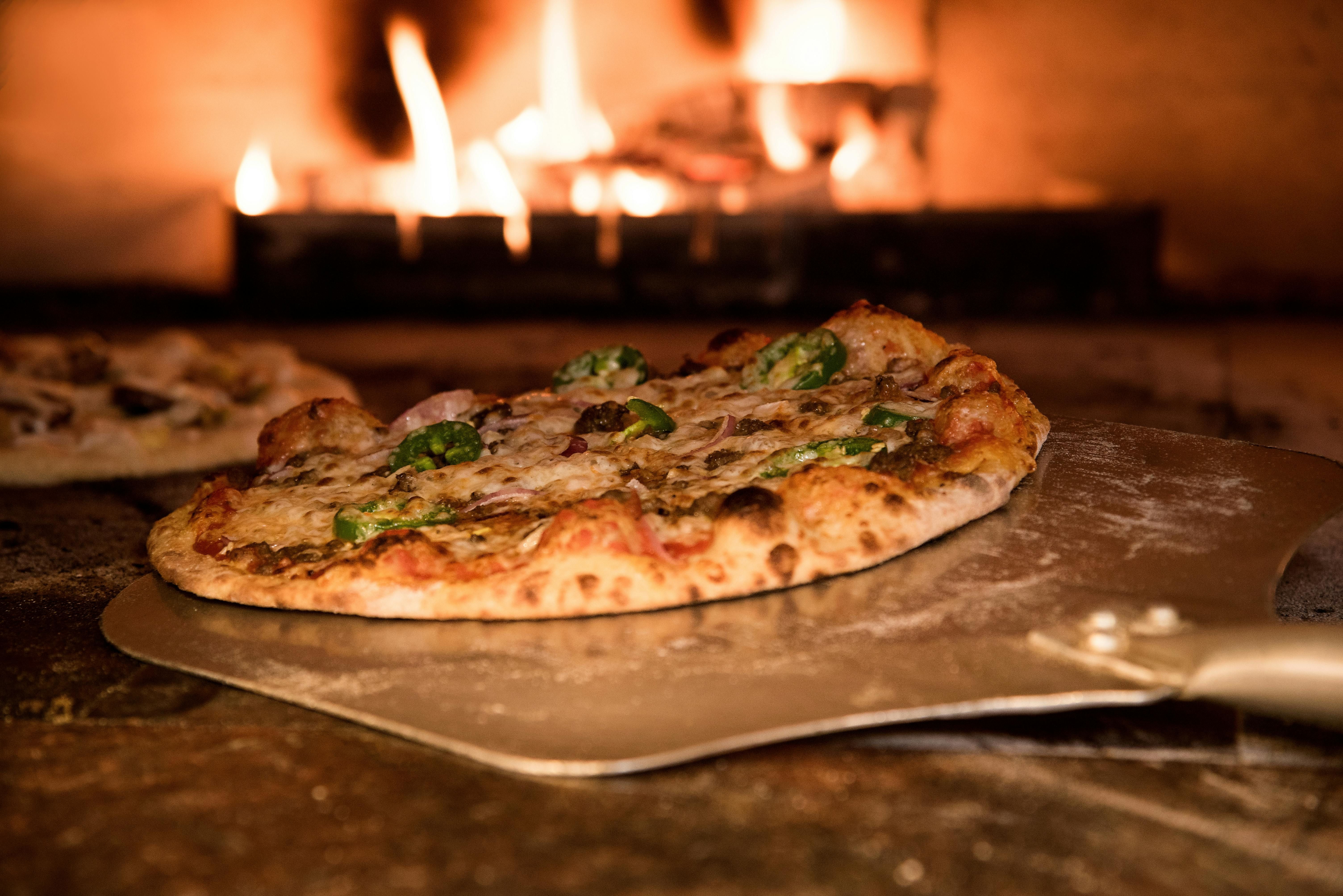 Chef preparing pizza in wood-fired oven